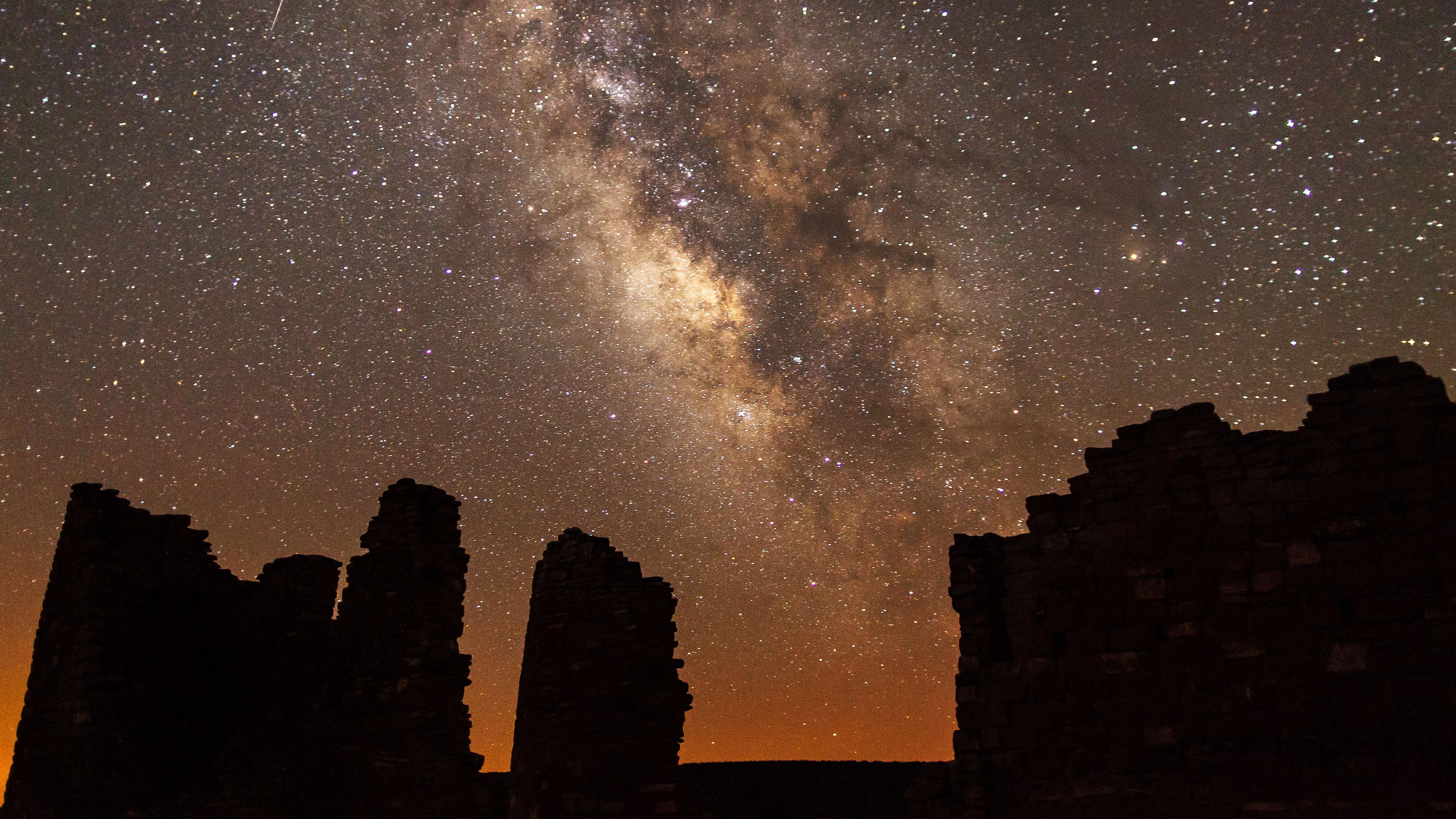 silhouetted structures with the night sky and Milky Way overhead.