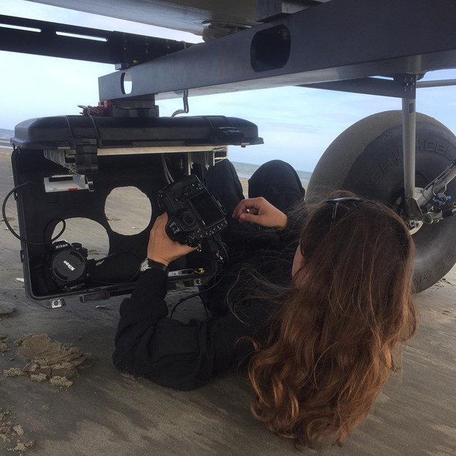A woman fits a camera into the belly of a small plane.