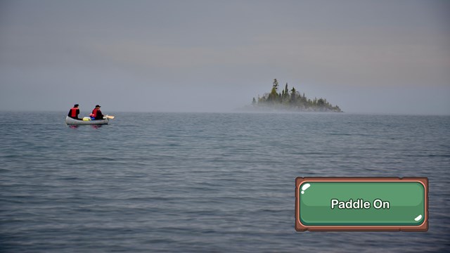 Two people paddle a canoe on a large lake in the fog.