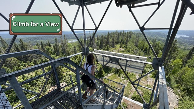 A person walking down the metal stairs of a fire tower.
