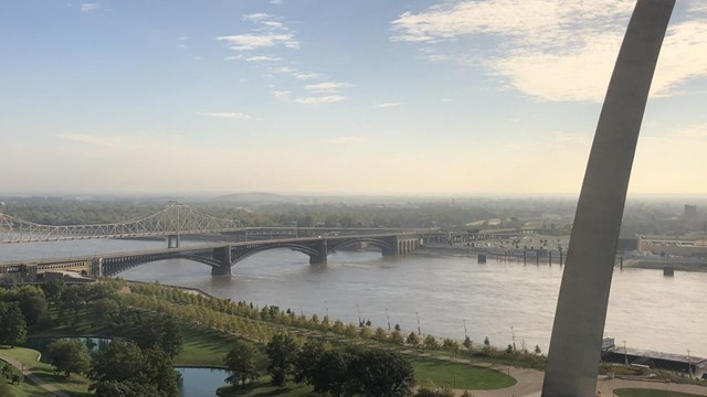 a view of the Gateway Arch grounds, river and the Eads bridge in the distance 