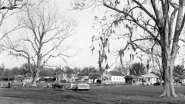 historic photo of neighborhood, old truck out  front, homes and trees