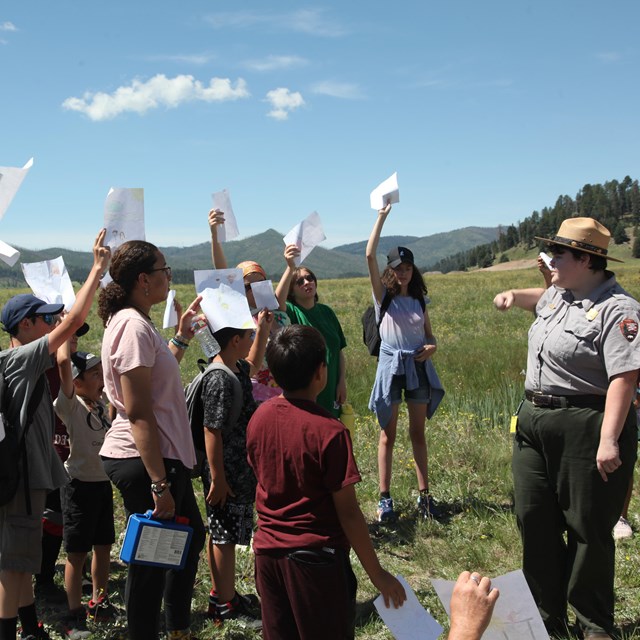 A park ranger addresses a group of students during a guided hike.