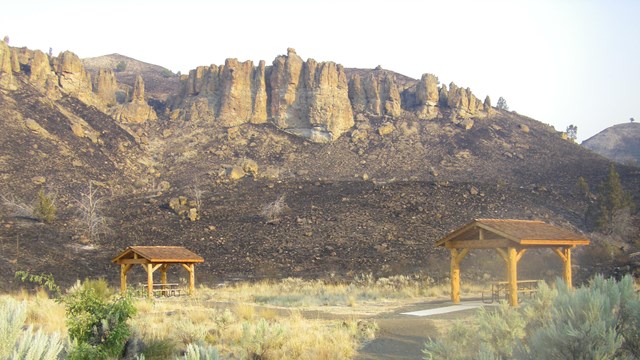 A picnic area with a burned hillside lacking any vegetation behind it.