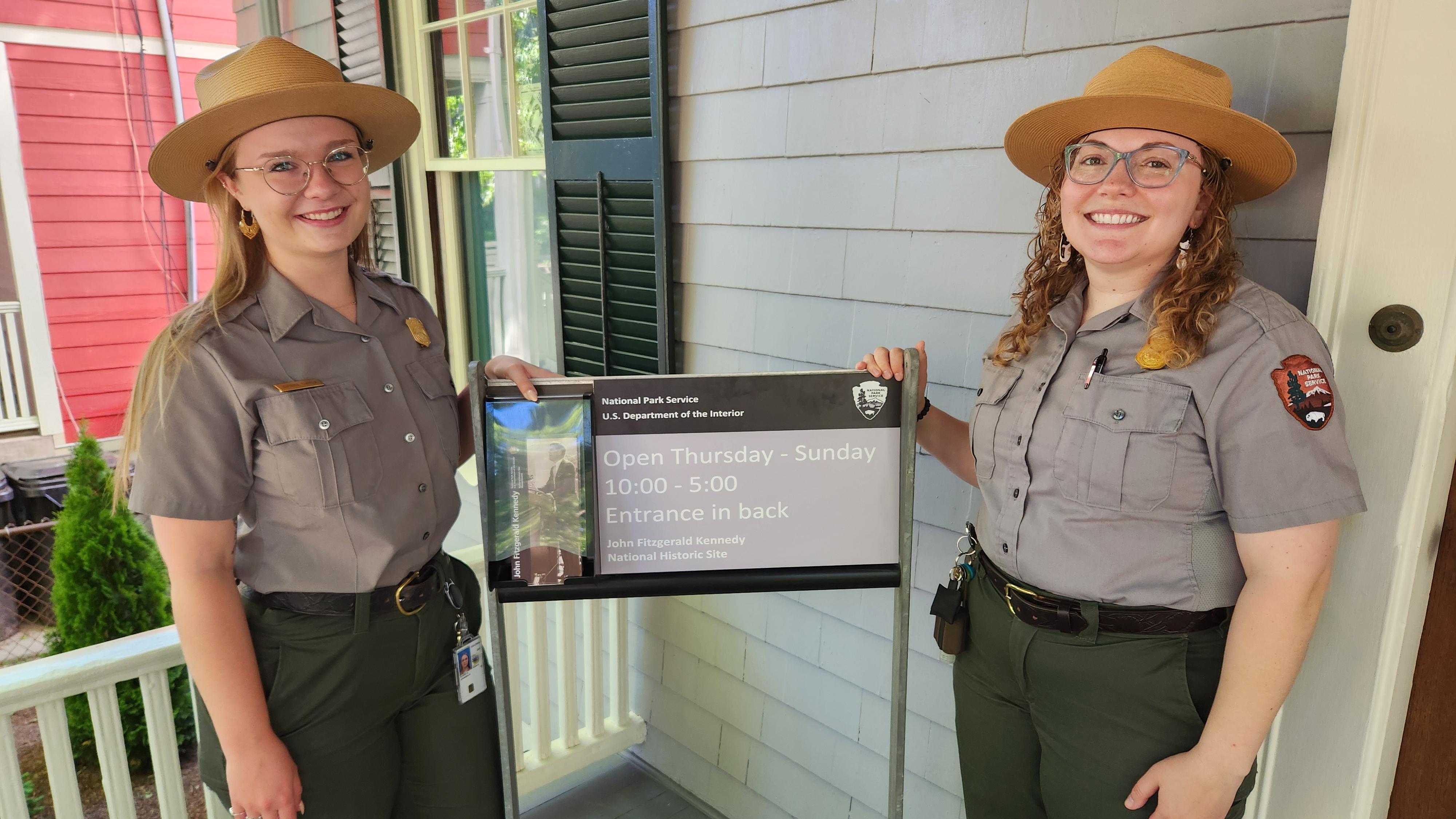 Park staff stand beside an open sign 