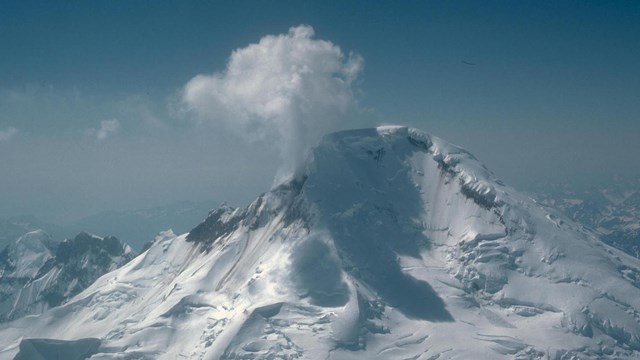 A steaming volcano covered in snow