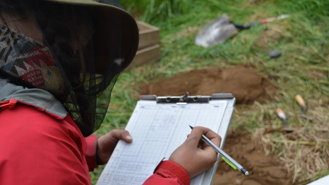 A scientist takes notes in the field