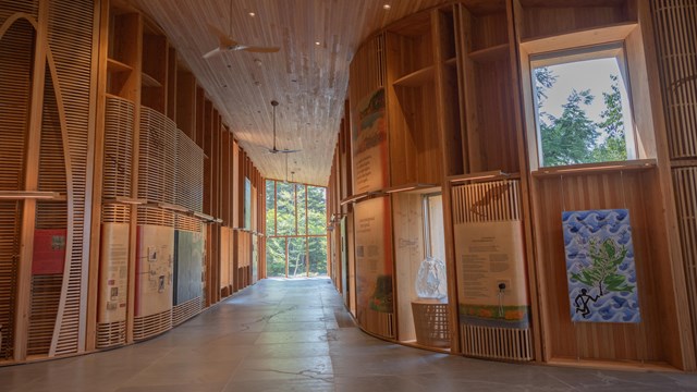 The inside of a wooden building with curved wood panels and stone tile floors.
