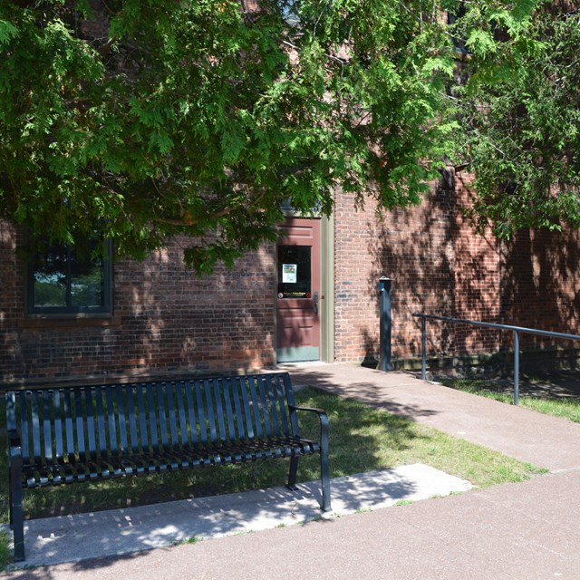 Paved ramp leading to a door in the side of a brick building.
