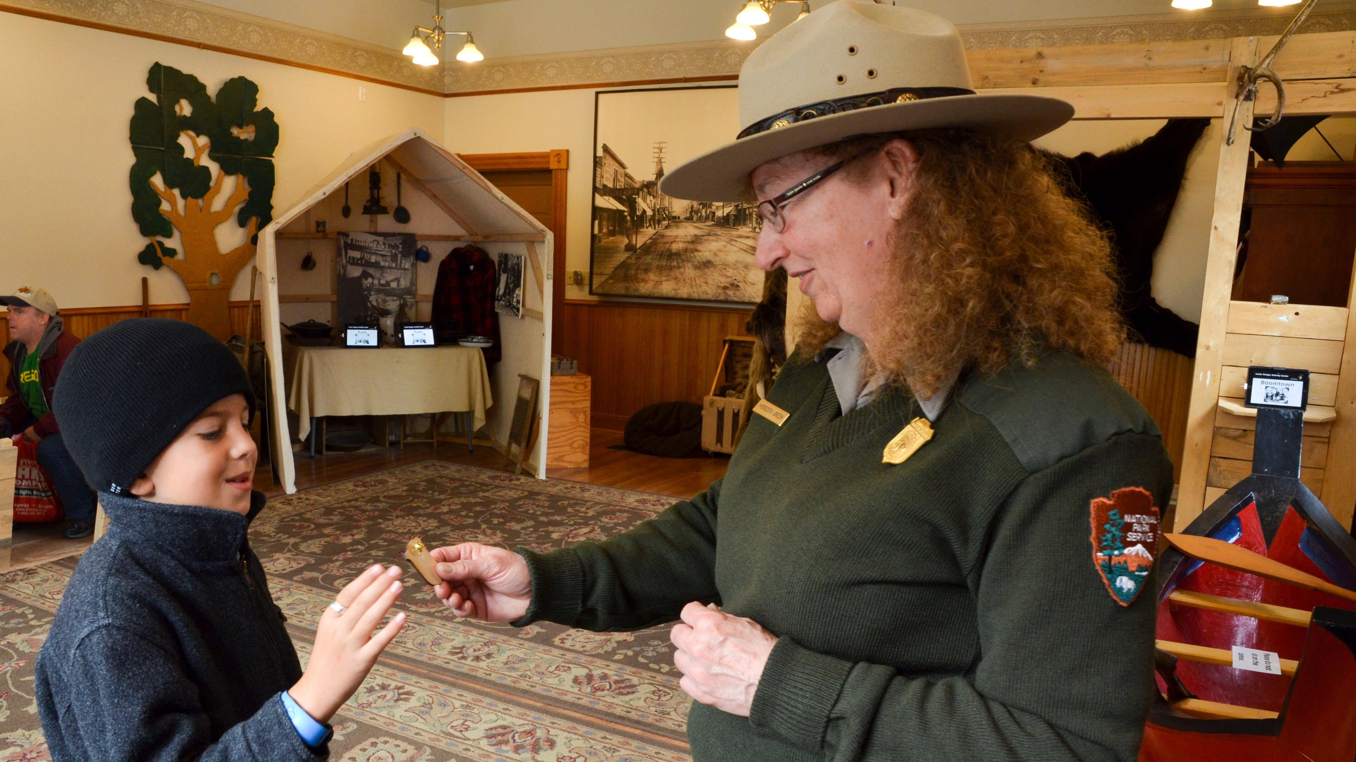 A ranger hands a badge to a boy