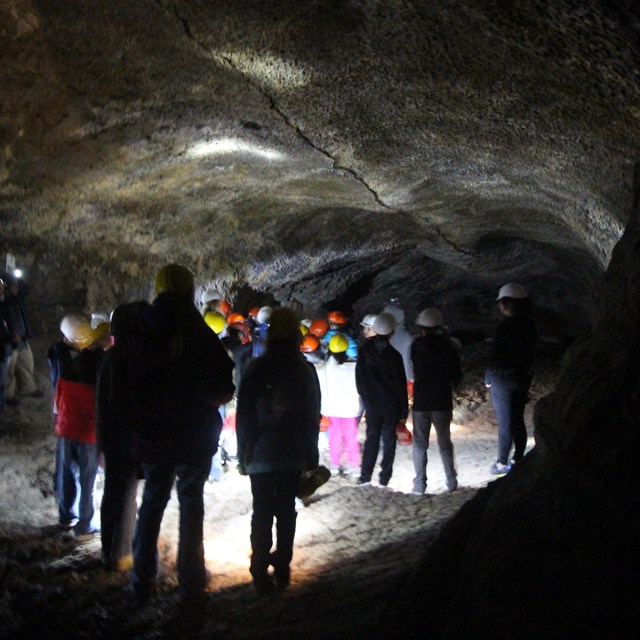 A cave illuminated by lights of a school group.