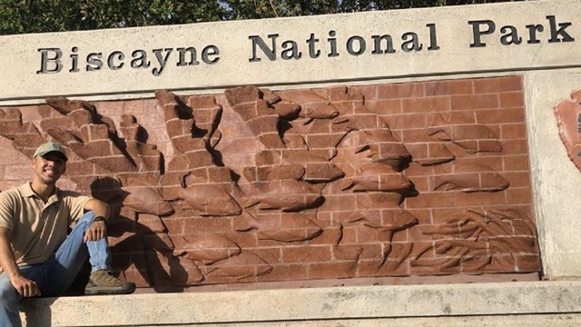 Intern standing next to Biscayne National Park Service Sign 