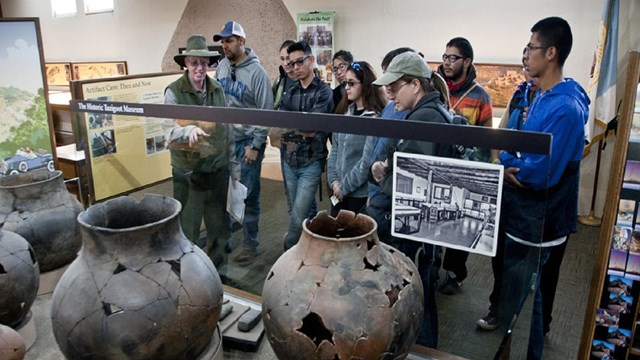 A group of students look at large earthenware pots.