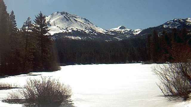 A snow-covered lake and peak in background