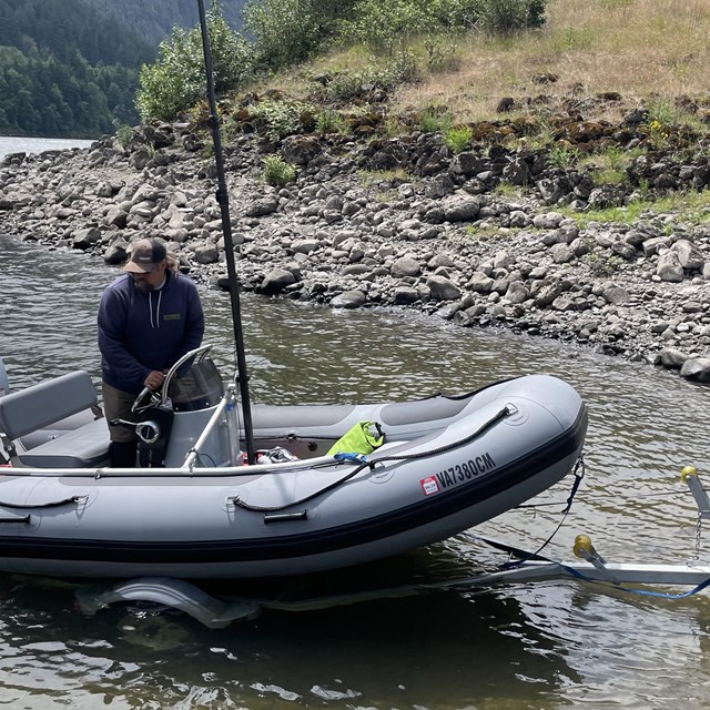 two men load a boat on a river