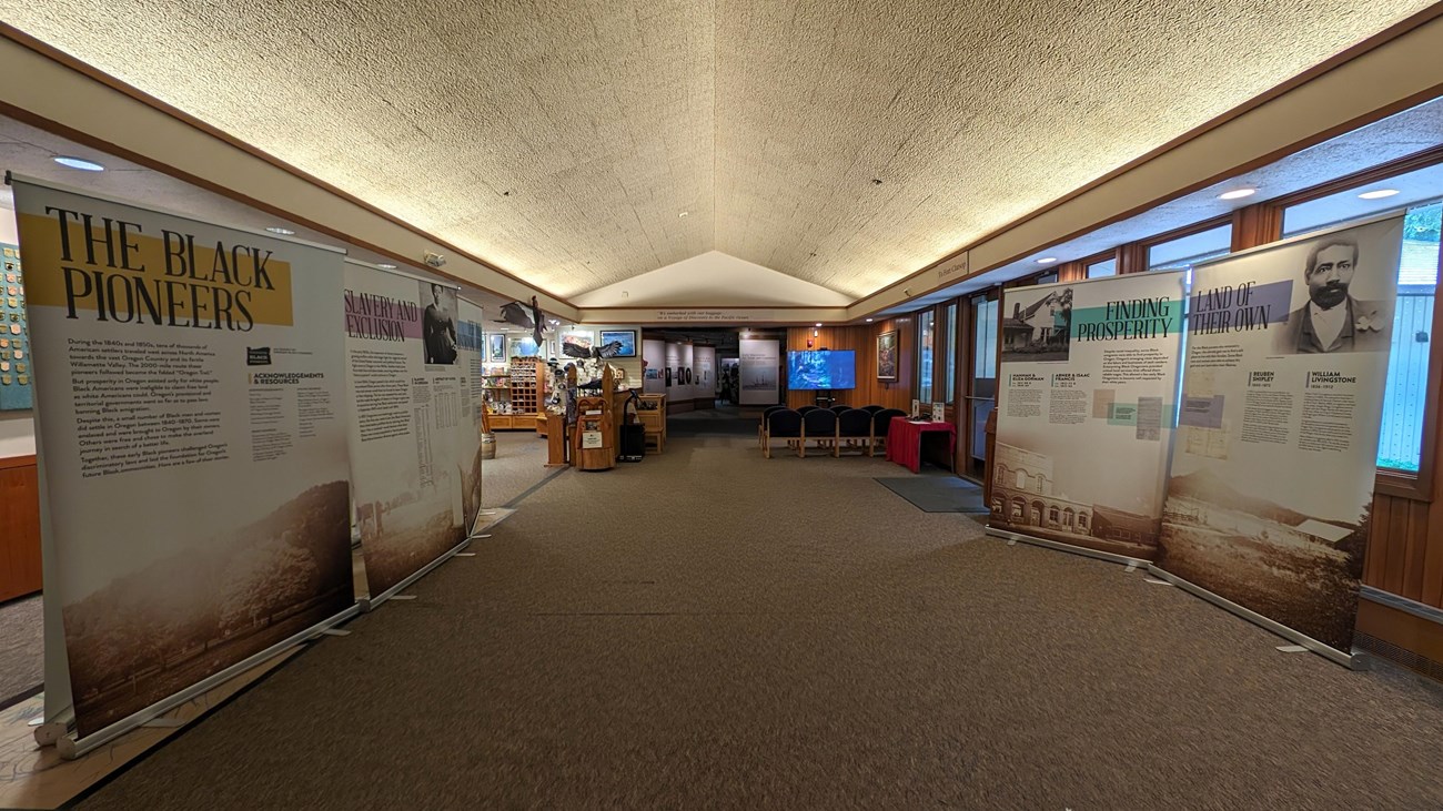 A visitor center lobby with displays of the Oregon Black Pioneer exhibit on either side.