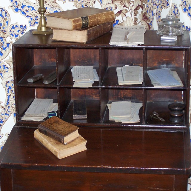 Small wooden writing desk with 8 pigeon hole drawers at back of desk