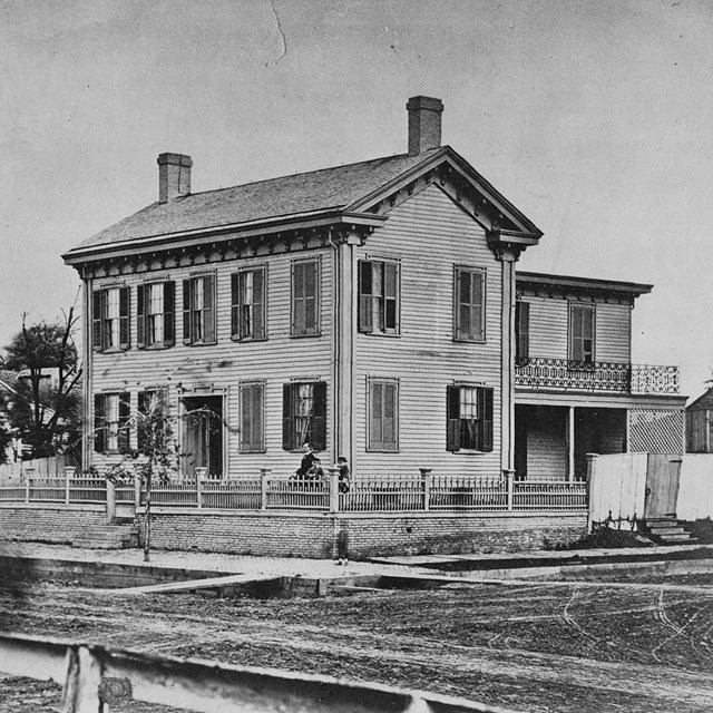 Black and White photo of Lincoln Home, a wooden 2 story house with back side porch and 2 chimneys