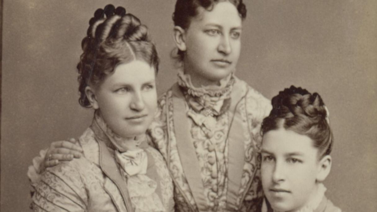 Seated portrait of three white woman with dark hair.
