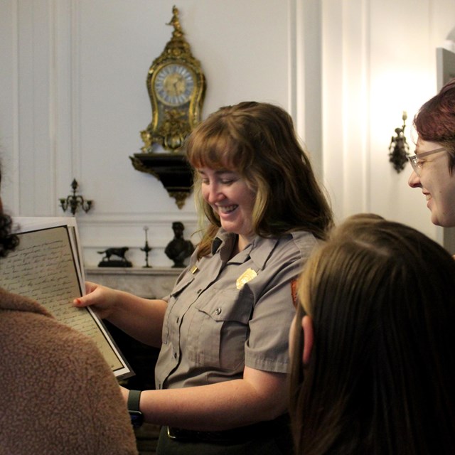Visitors with backs to the camera, ranger facing camera in a Victorian parlor