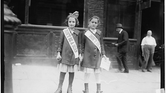 Two young girls on roller skates wearing sashes that read "don't be a scab"