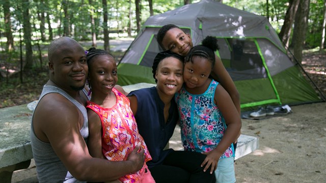 A family gathers at a picnic table near their tent in Mammoth Cave Campground.
