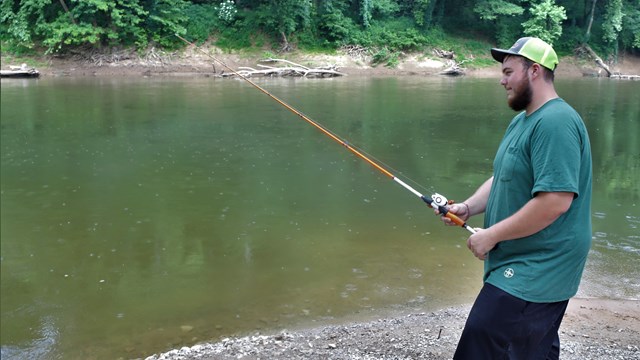 A young man fishing along a river