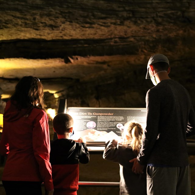 A family reading a sign in the cave. 