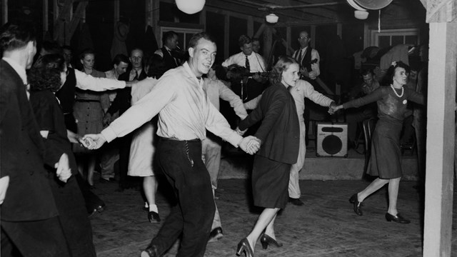 Black and white photo of people dancing while hands are joined