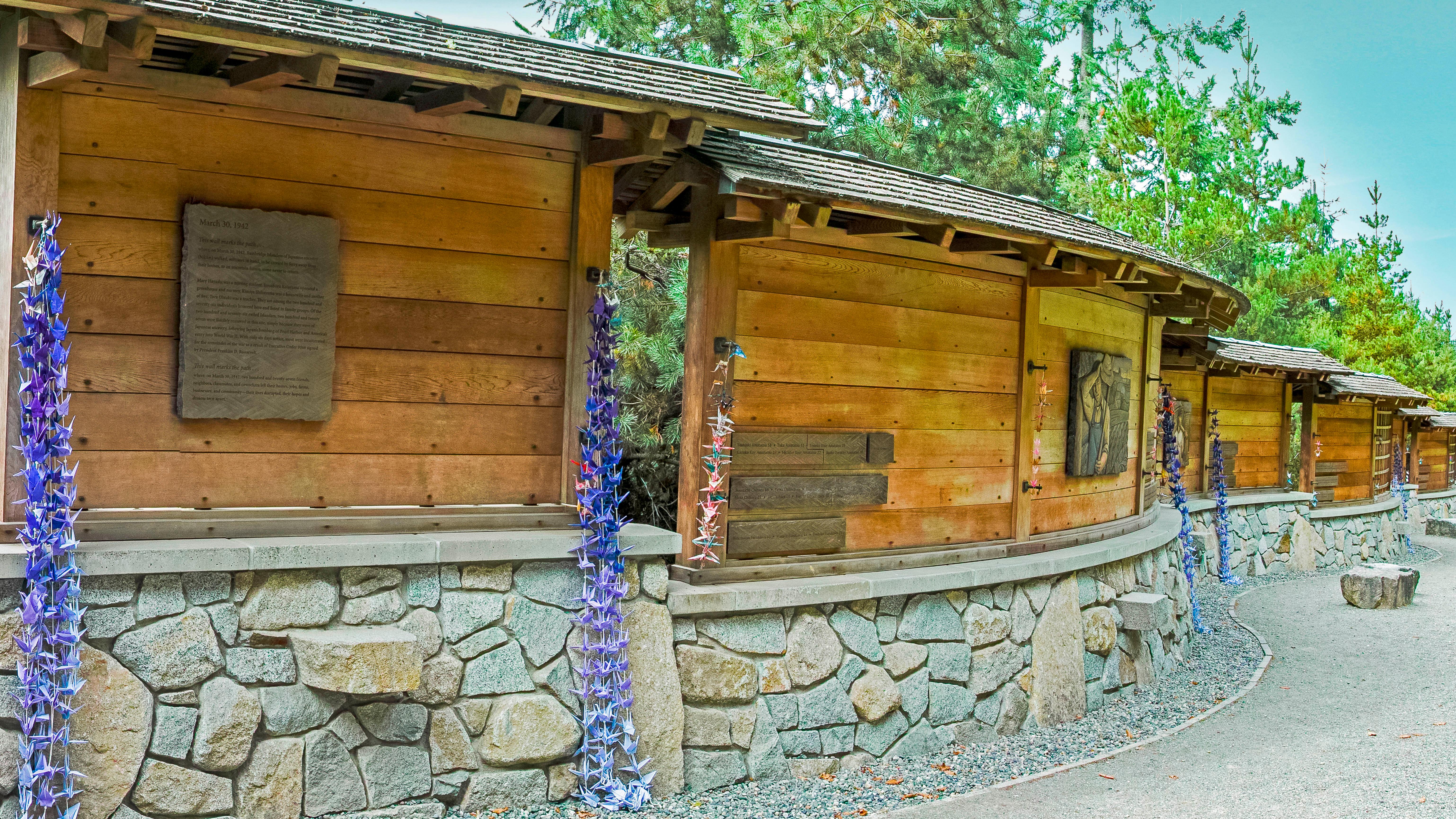 Wooden and stone memorial that curves along a sidewalk.
