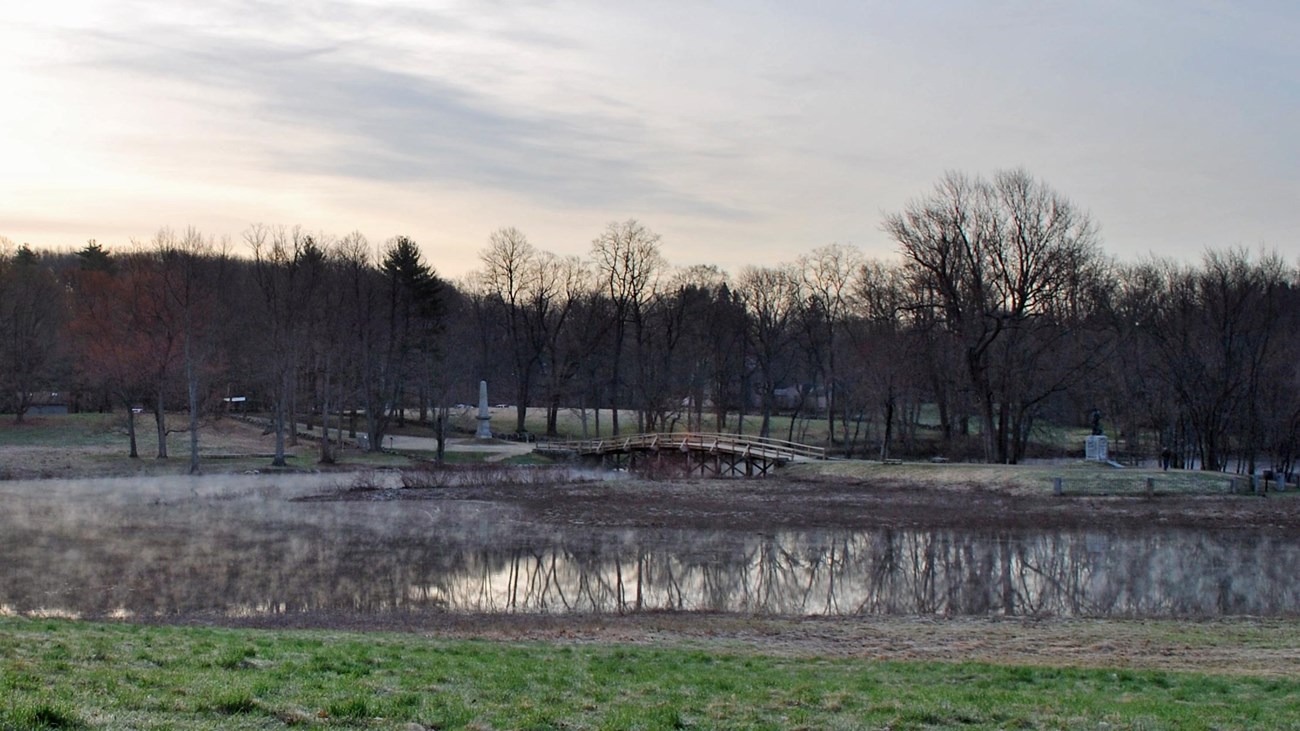 A wooden bridge spans the Concord river. Water has flooded the banks