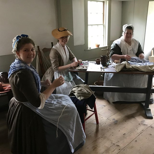 Three women sit in the 18th century kitchen of Hartwell Tavern