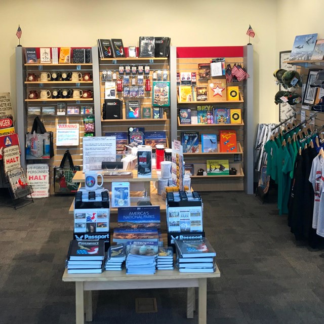 Small room with shelves of books, souvenirs, and other sales items arranged on a table and the wall