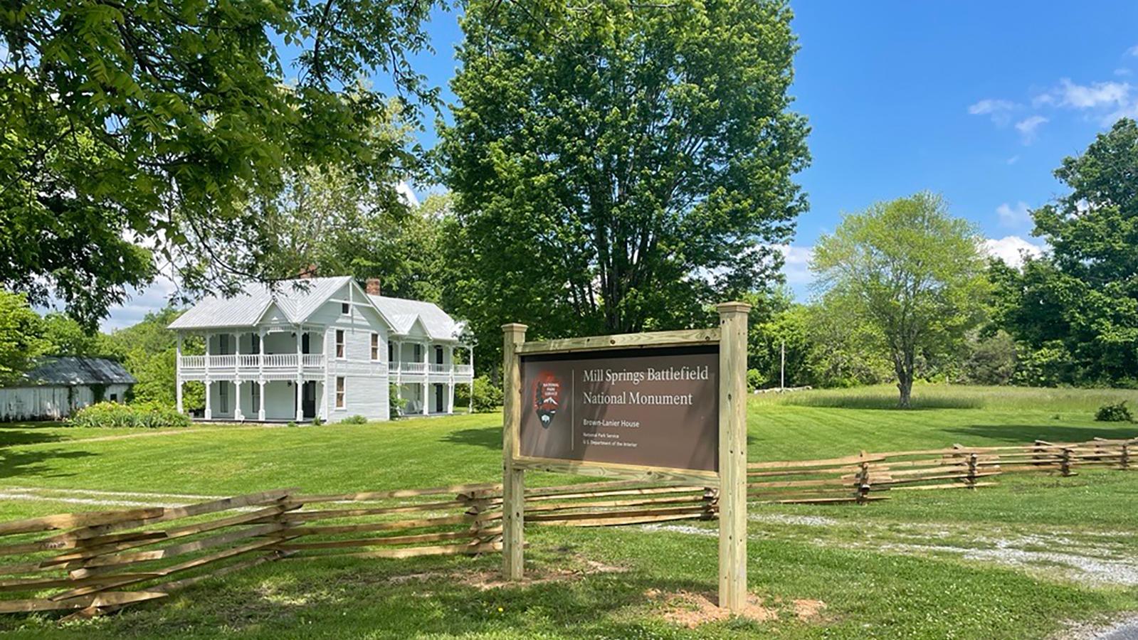 The NPS sign in front of a white house and green grass.