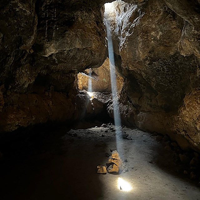 Inside a lava tube with beams of light from the surface