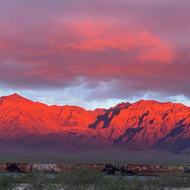 Mountains in the desert with a reddish glow from the sunset.