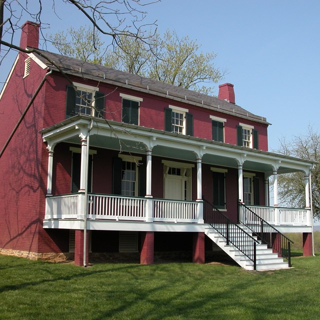 Two story red brick farmhouse with a front porch.