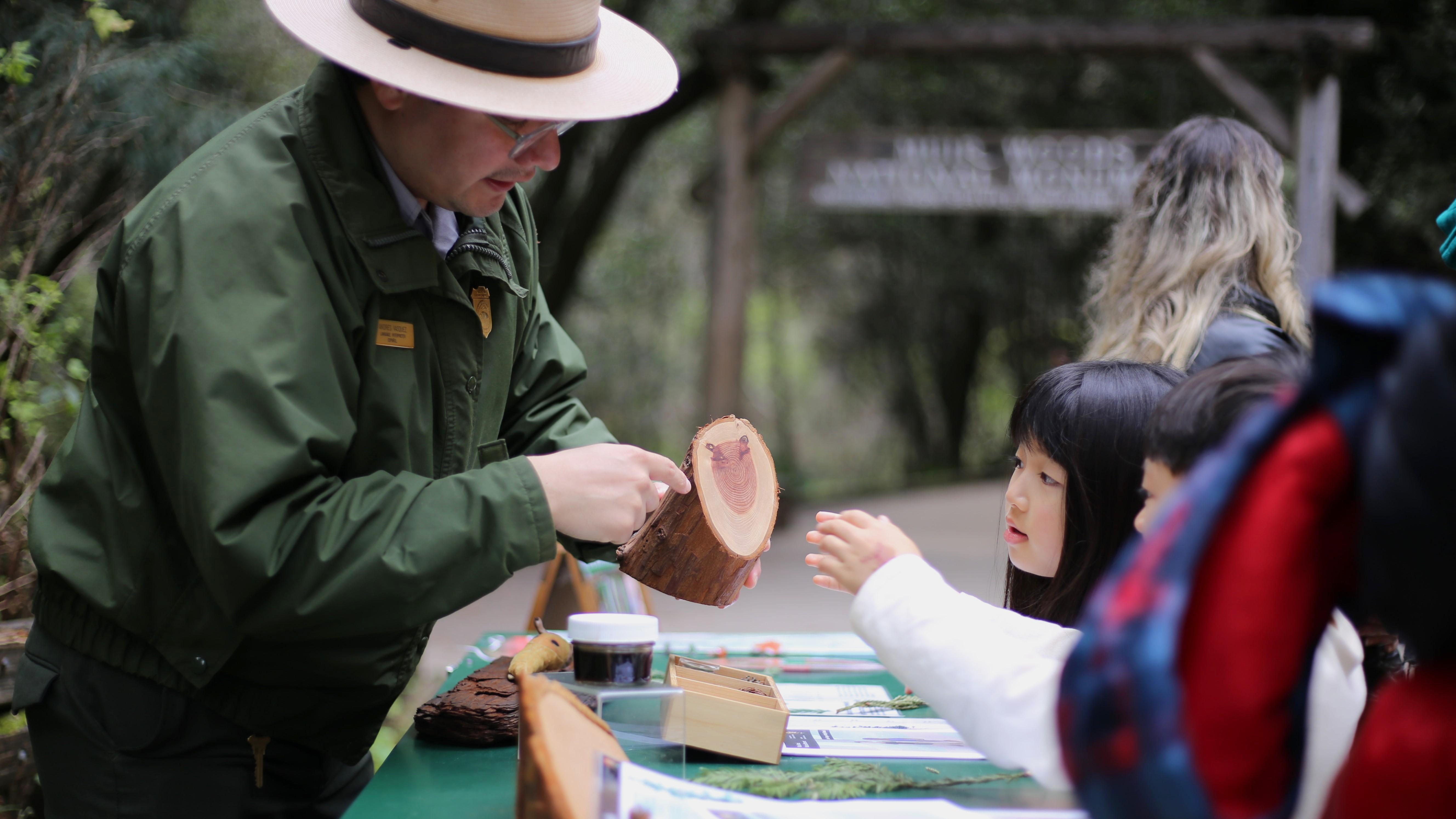 a ranger talks with kids about a tree trunk