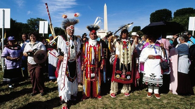 Native Americans in traditional dress with the Washington Monument in the background