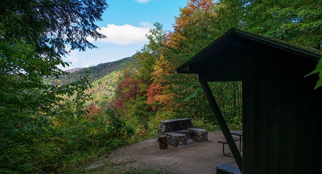 Image of a mountain overlook. There is a small, wooden outpost to the right of the image.