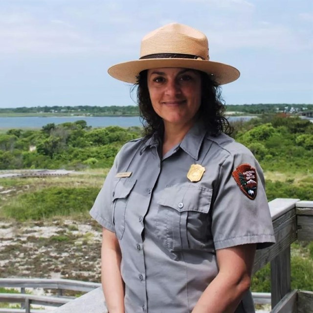 A park ranger in tan ranger hat and grey-blue short-sleeved NPS collared button-down