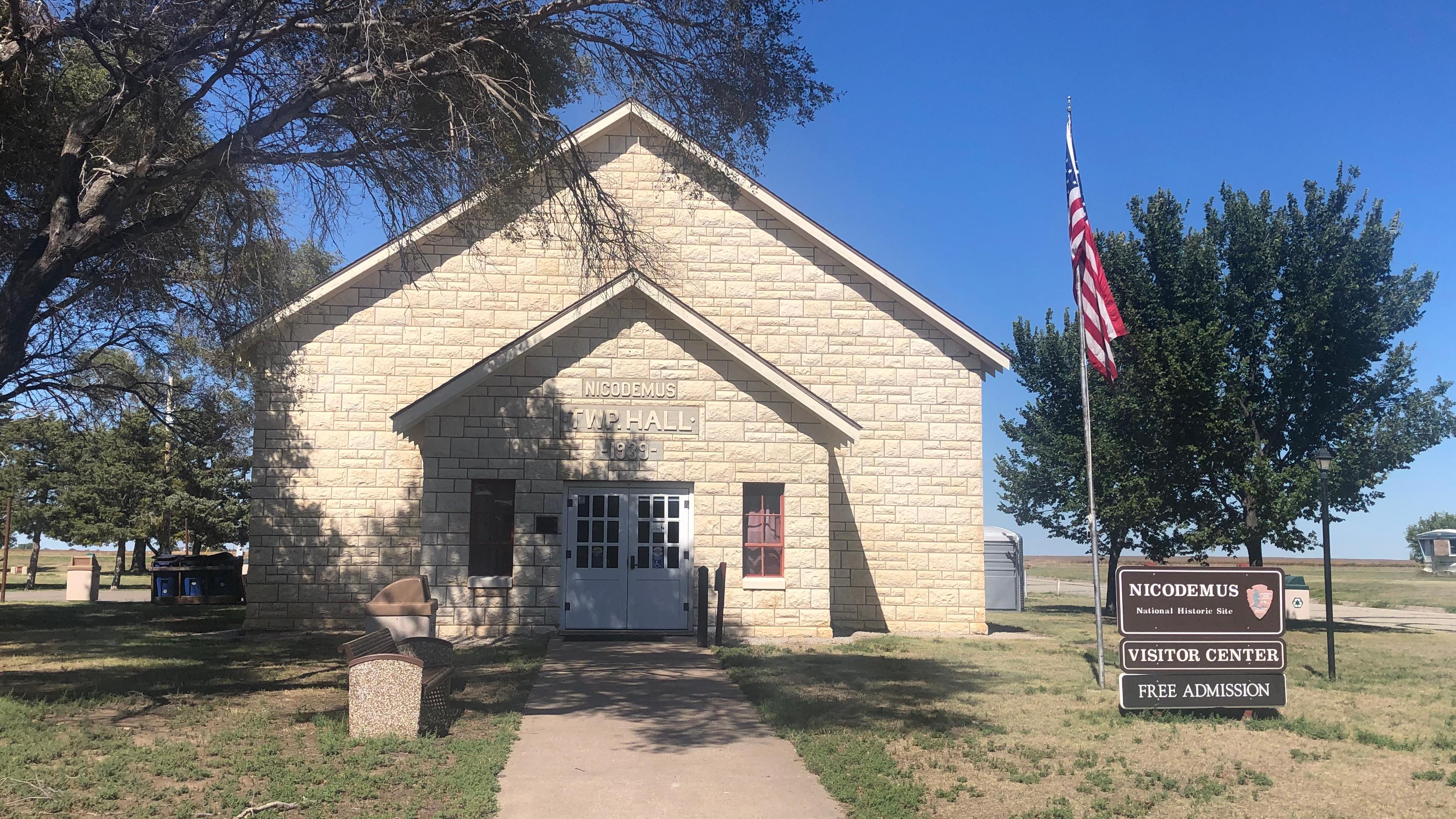 A limestone building with an American flag and park sign.