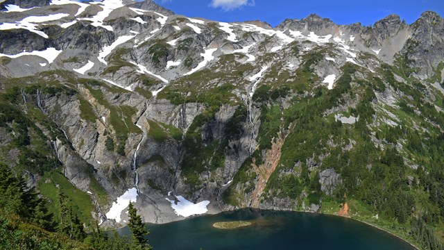 An alpine lake with sparse snow on a mountainside