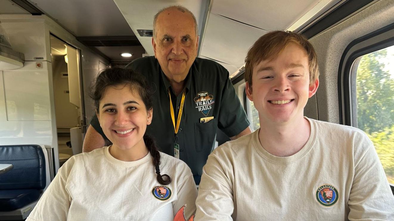 Trails & Rails volunteers smiling onboard an Amtrak train 