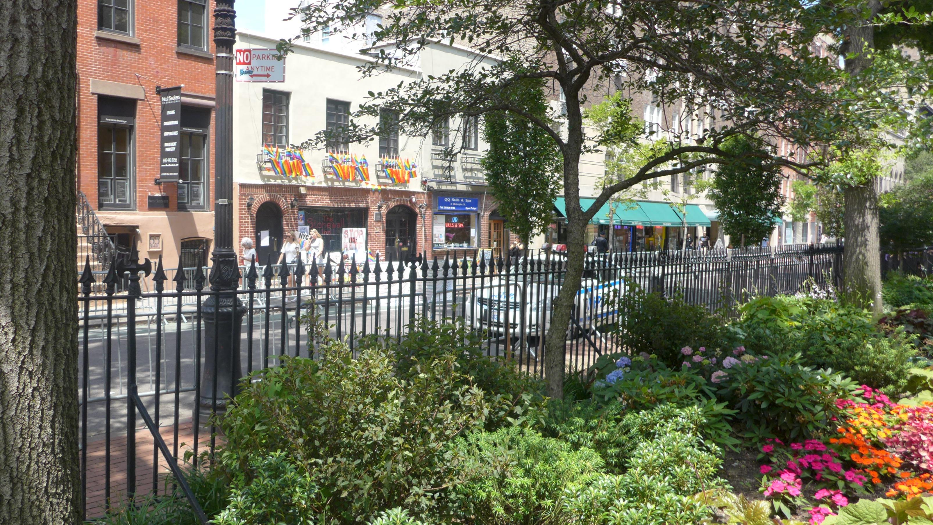 Brick building with iron fence and flowers out front