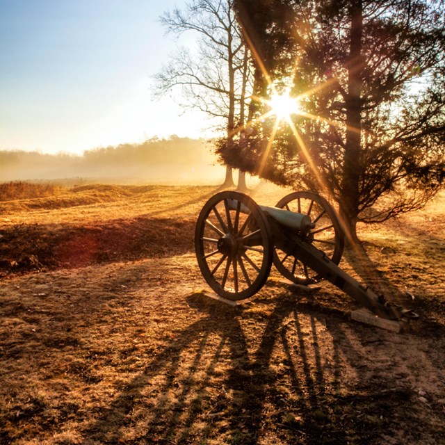 19th century cannon on a farm field during sunset