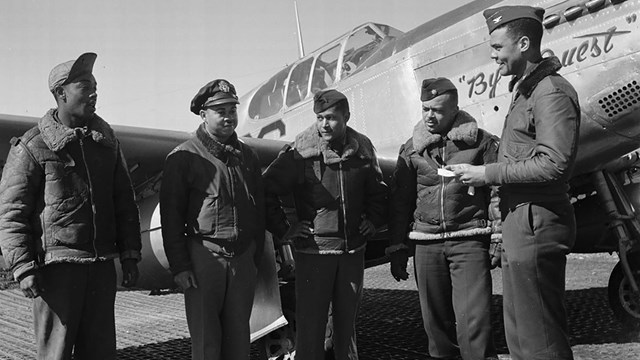  Col. Benjamin Oliver Davis presents a war bond to four airmen in front of a fighter jet, 1945