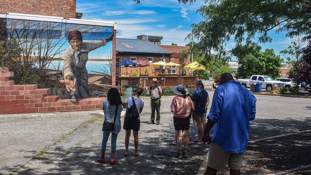 Ranger giving a tour in front of a mural of Harriet Tubman