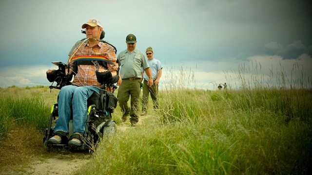 Several National Park Service employees on a trail in a prairie