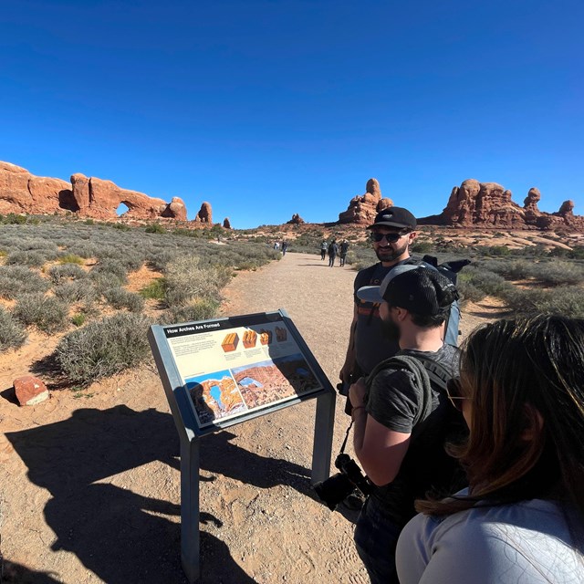 Visitors reading a park sign in a desert